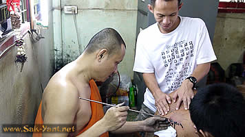 The monk is engraving the tattoo
